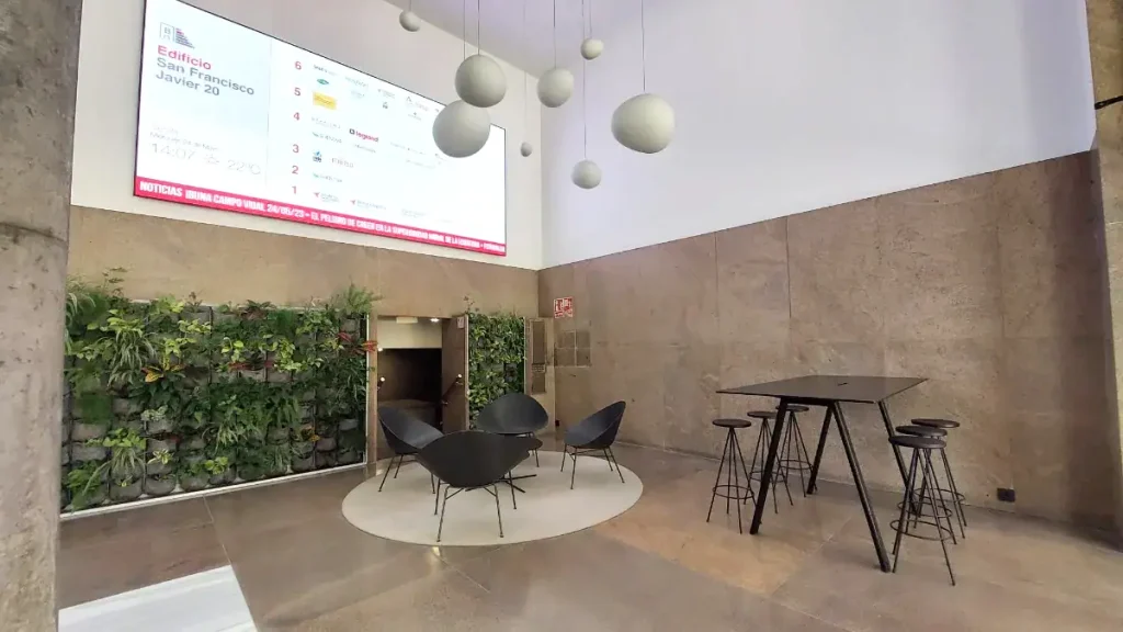 Hall de acceso con jardín vertical y zona de espera en edificio San Francisco Javier 20, INN Offices Nervión, Sevilla