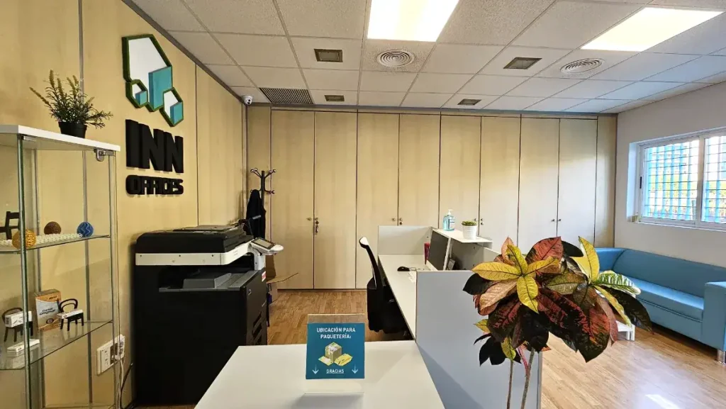 Zona de recepción con logo INN Offices, impresora y área de espera en centro de negocios Aljarafe, Sevilla