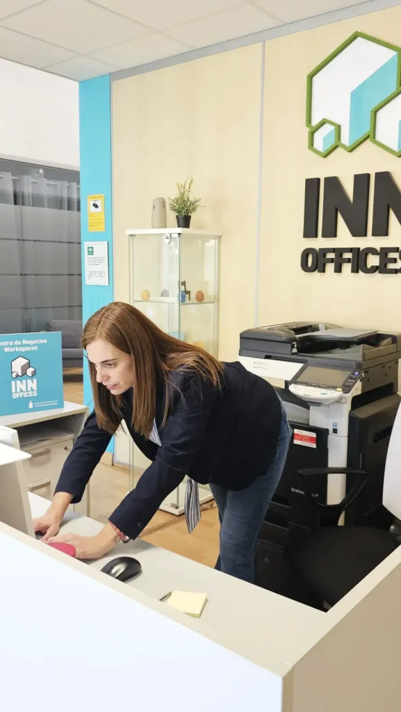 Recepcionista trabajando en mostrador con logo INN Offices en centro de negocios Aljarafe, Sevilla