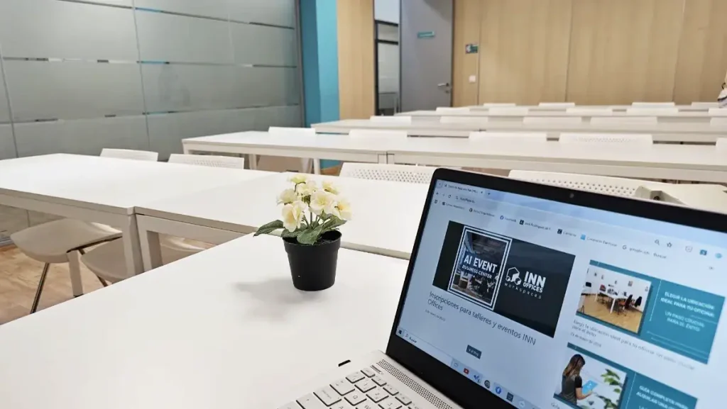 Sala de formación con mesas y portátil en centro de negocios INN Offices Aljarafe, Sevilla